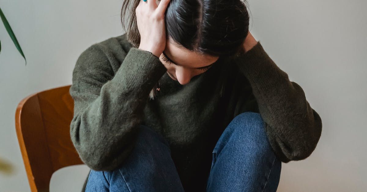 A woman is sitting in a chair with her head in her hands.