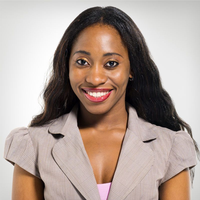 A woman wearing a grey jacket and pink shirt smiles for the camera