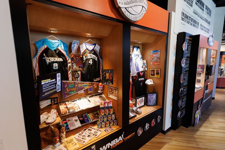 Indoor exhibition booth with colorful posters, hanging lights, and large display banners