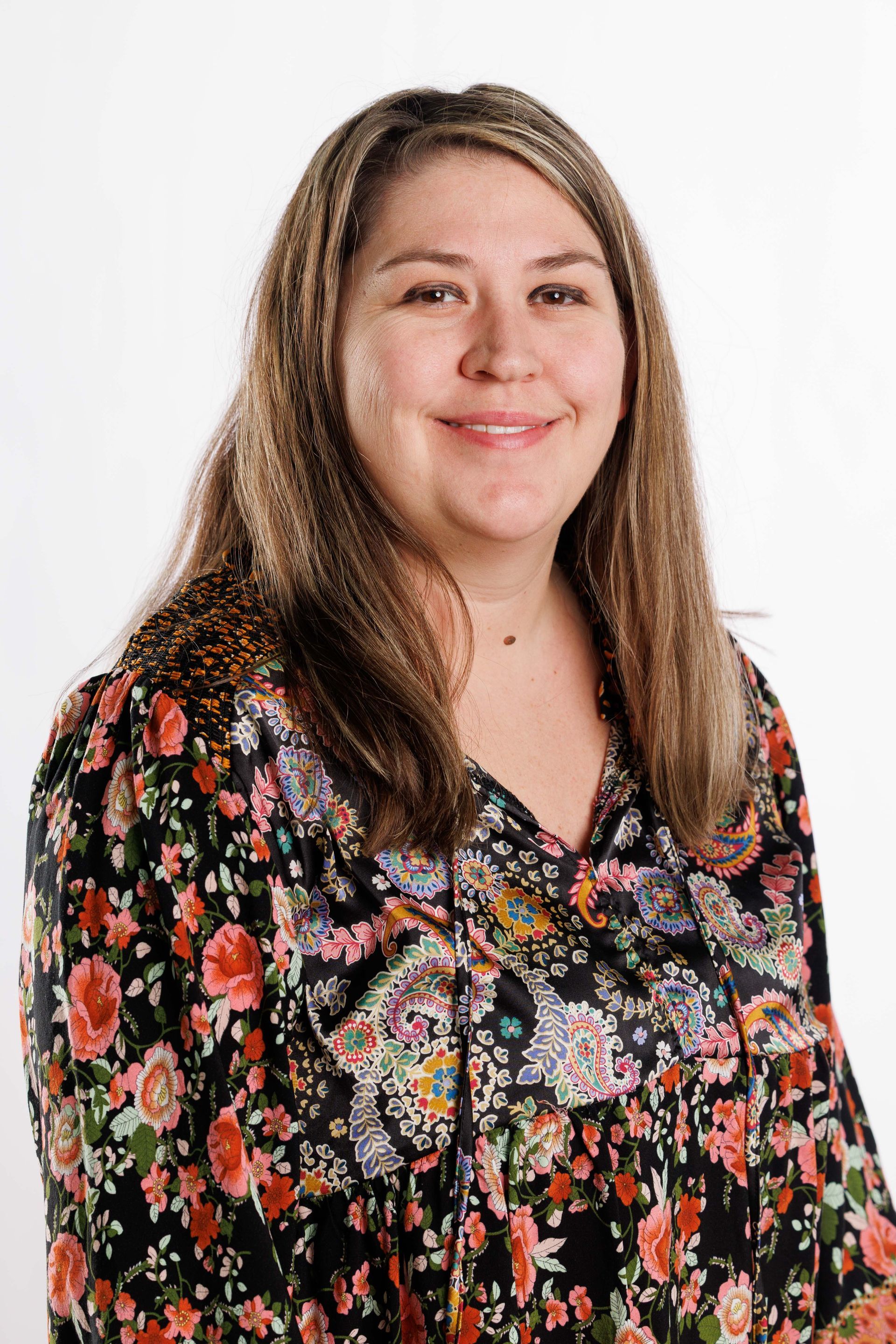 Smiling woman in a black floral blouse against a plain white background
