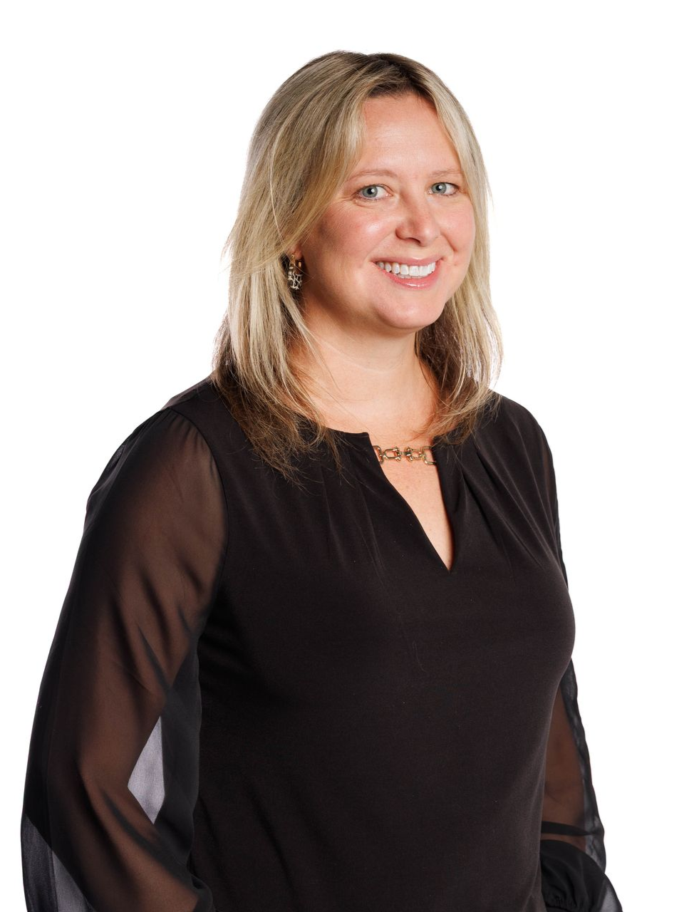 Portrait of a smiling person in a black top and patterned blazer against a white background