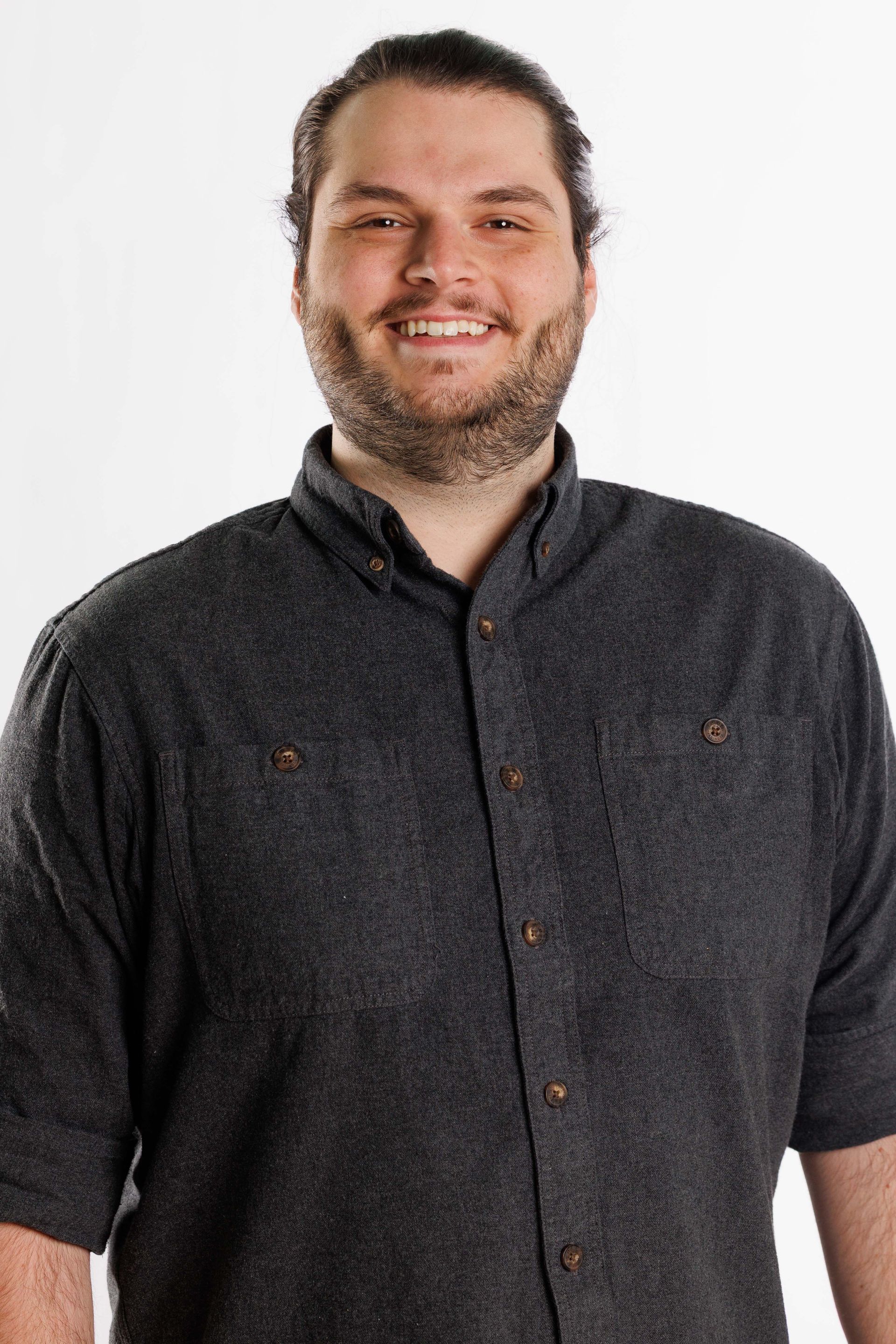 Smiling person in a dark button-up shirt against a white background