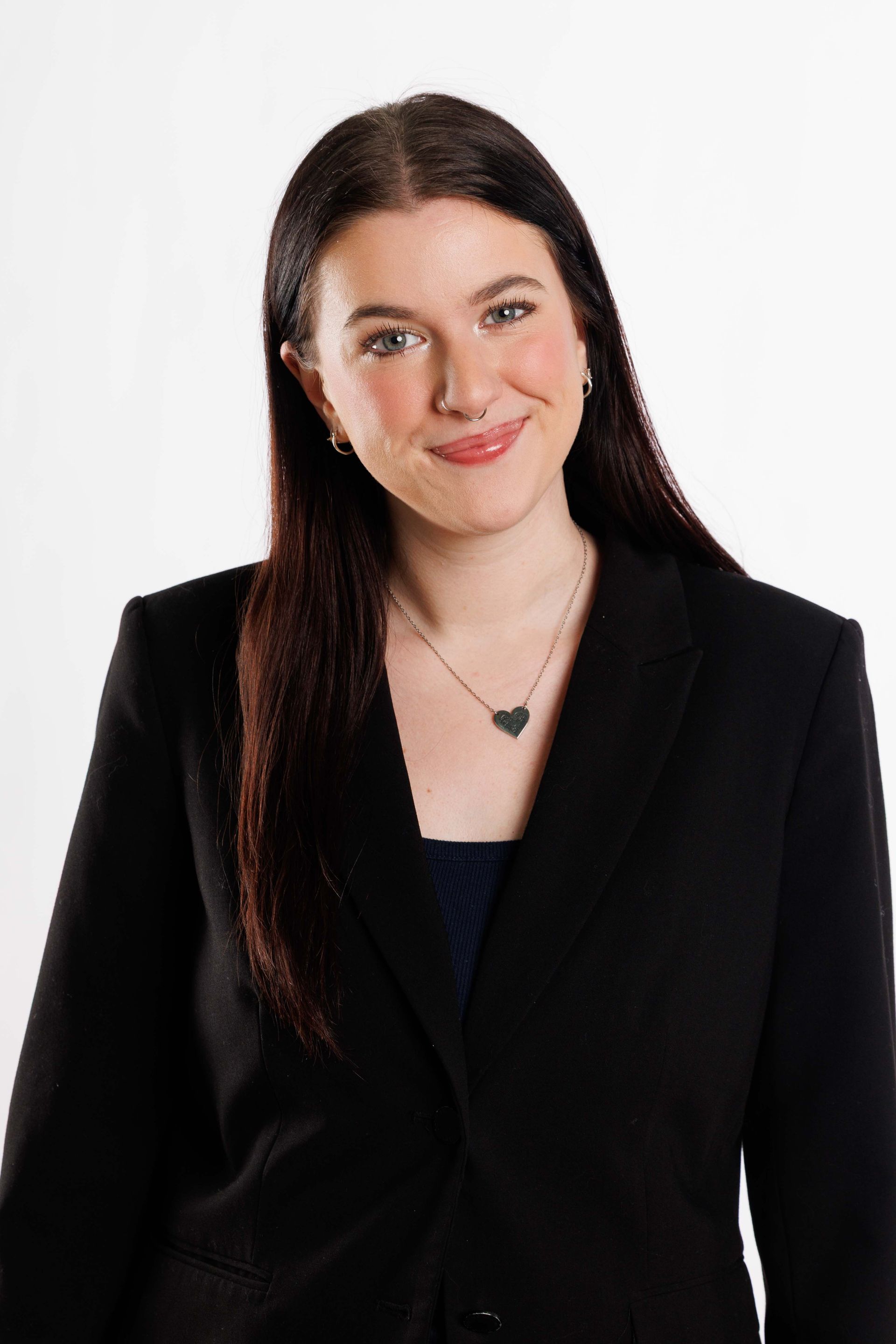 Woman in a black blazer smiling against a plain white background