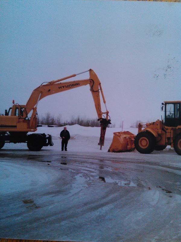 Un homme se tient devant une excavatrice Hyundai