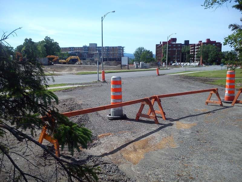 Un chantier de construction avec des cônes orange et blancs et une barrière en bois