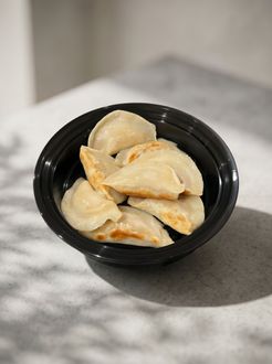 Black bowl of dumplings on a gray countertop in soft natural light