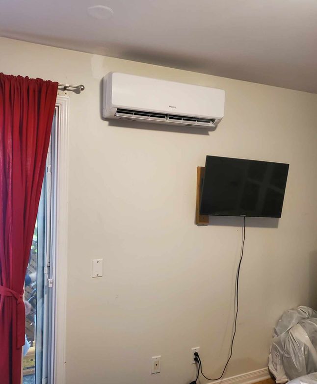 Mur avec climatiseur et télévision fixés au-dessus d'une prise électrique, à côté d'un rideau rouge.