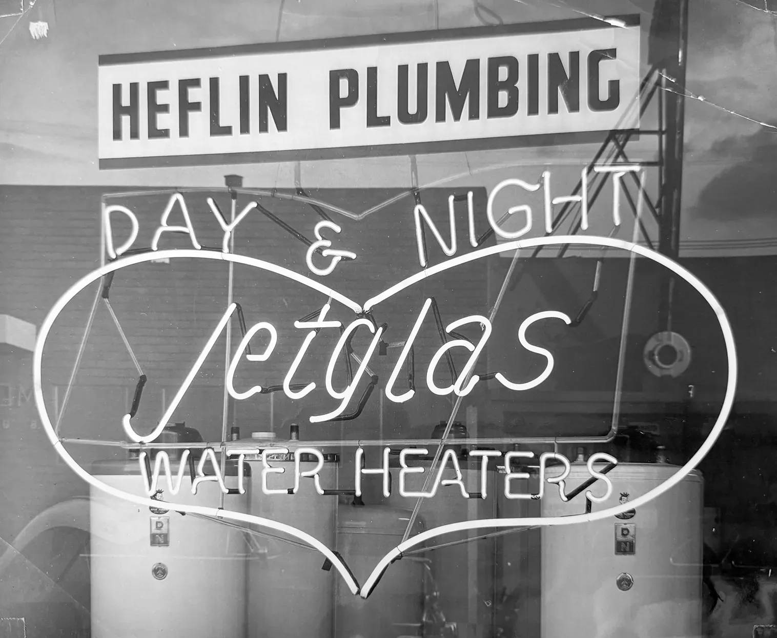 Historic Heflin Plumbing storefront sign advertising day and night plumbing service.