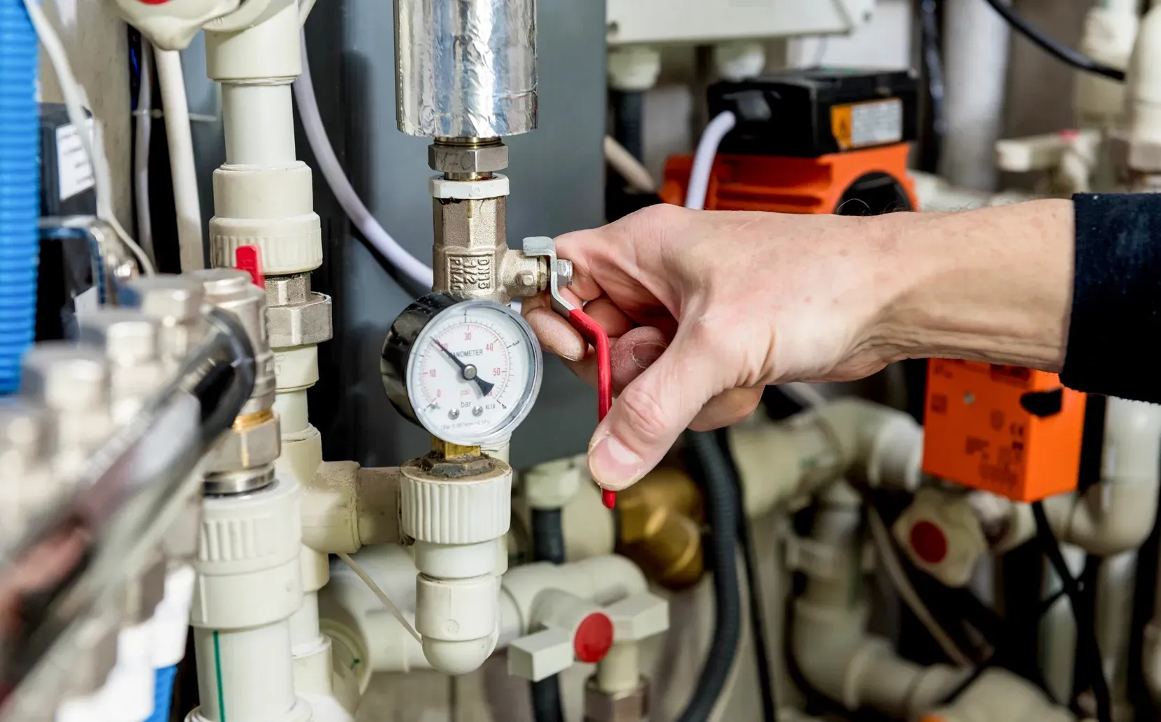 Technician inspecting a residential heating system pressure gauge during professional heating service.