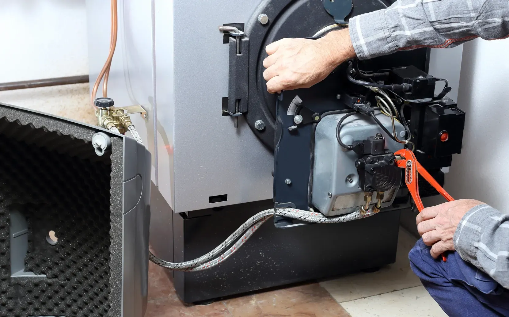 Technician servicing residential heating equipment during a heating repair and system inspection.