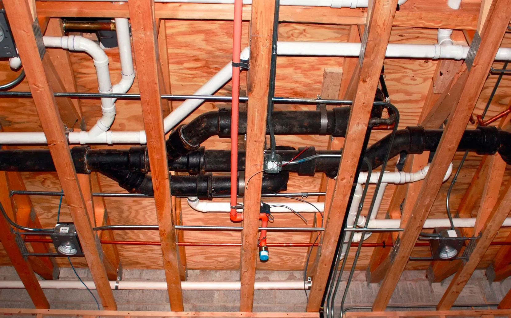 Residential plumbing pipes and water lines installed beneath a home during a plumbing upgrade.