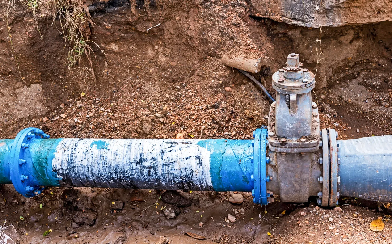 Exposed underground residential sewer line and valve during plumbing inspection and repair.