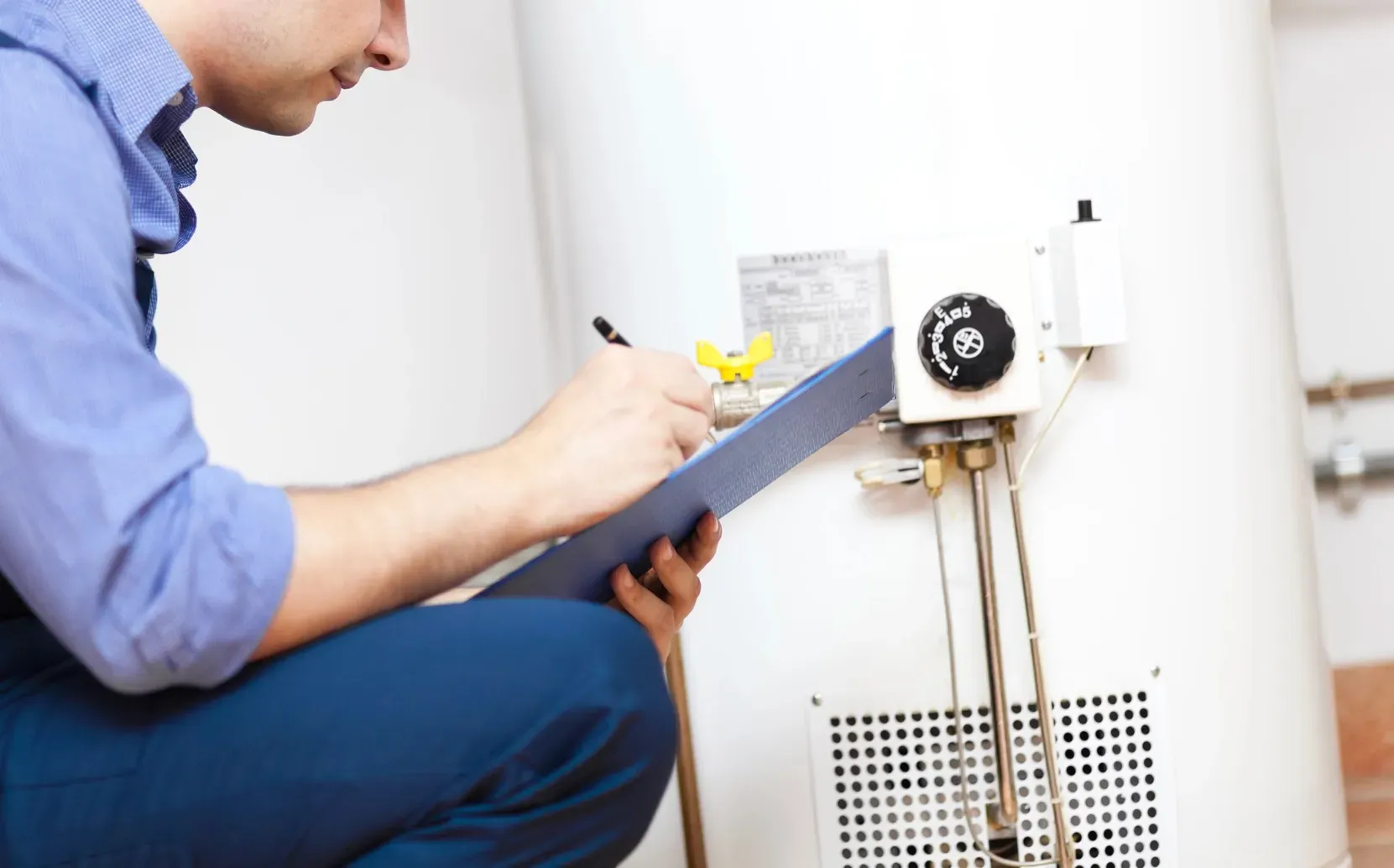 Technician performing routine maintenance and inspection on a residential water heater.