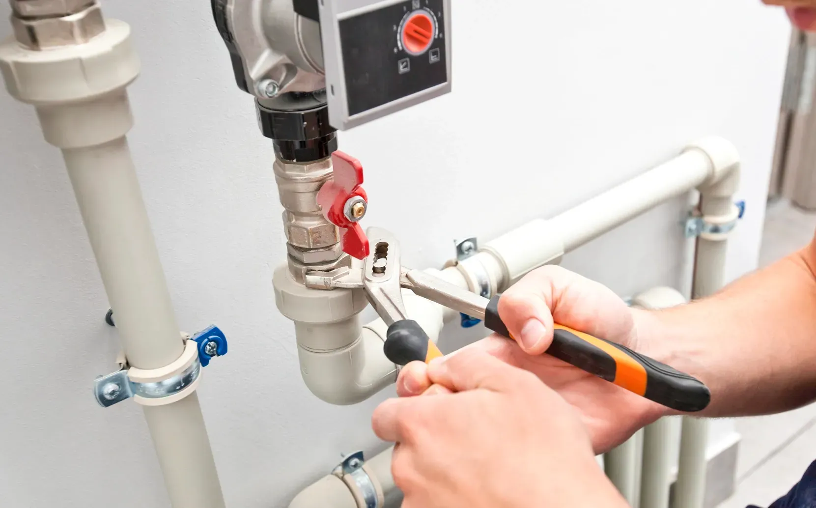Plumber servicing water heater pipes, valves and plumbing connections in a residential home.