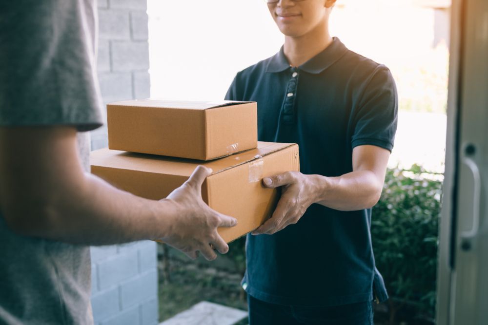 Delivery Person Handing Two Cardboard Boxes — JR Removals Mackay in Nebo, QLD