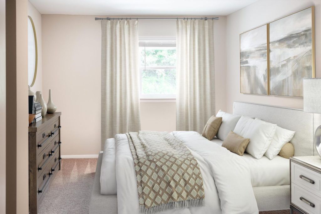 A bedroom with a bed, dresser, mirror, and window.