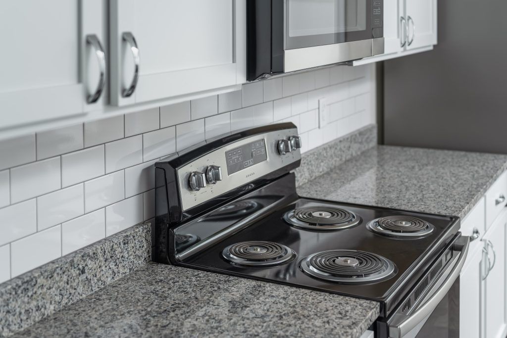 A stove top oven is sitting on top of a granite counter in a kitchen.