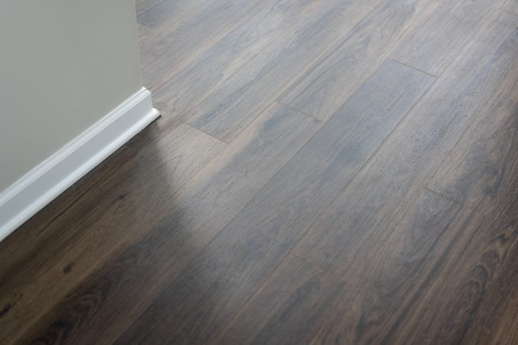 A close up of a wooden floor with a white trim.