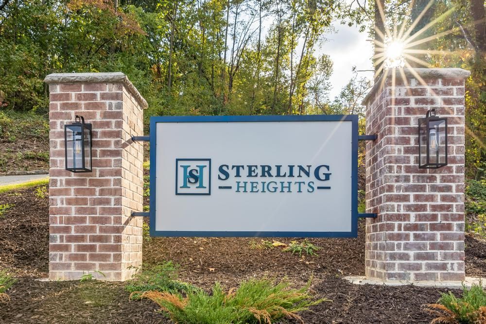 A sign for sterling heights is on a brick wall.