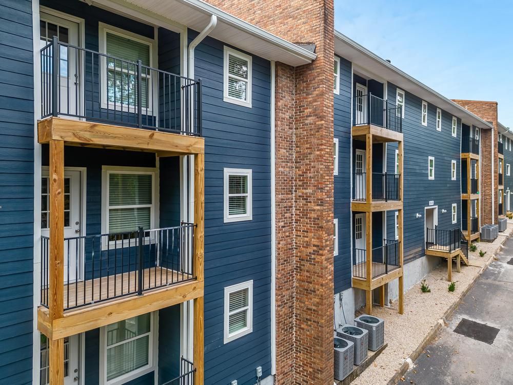 A large apartment building with blue siding and wooden balconies.