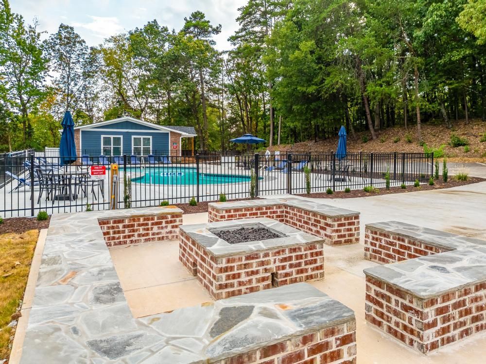 There is a fire pit in the middle of the patio next to a pool.