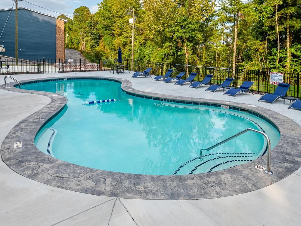 A large swimming pool surrounded by chairs and trees.