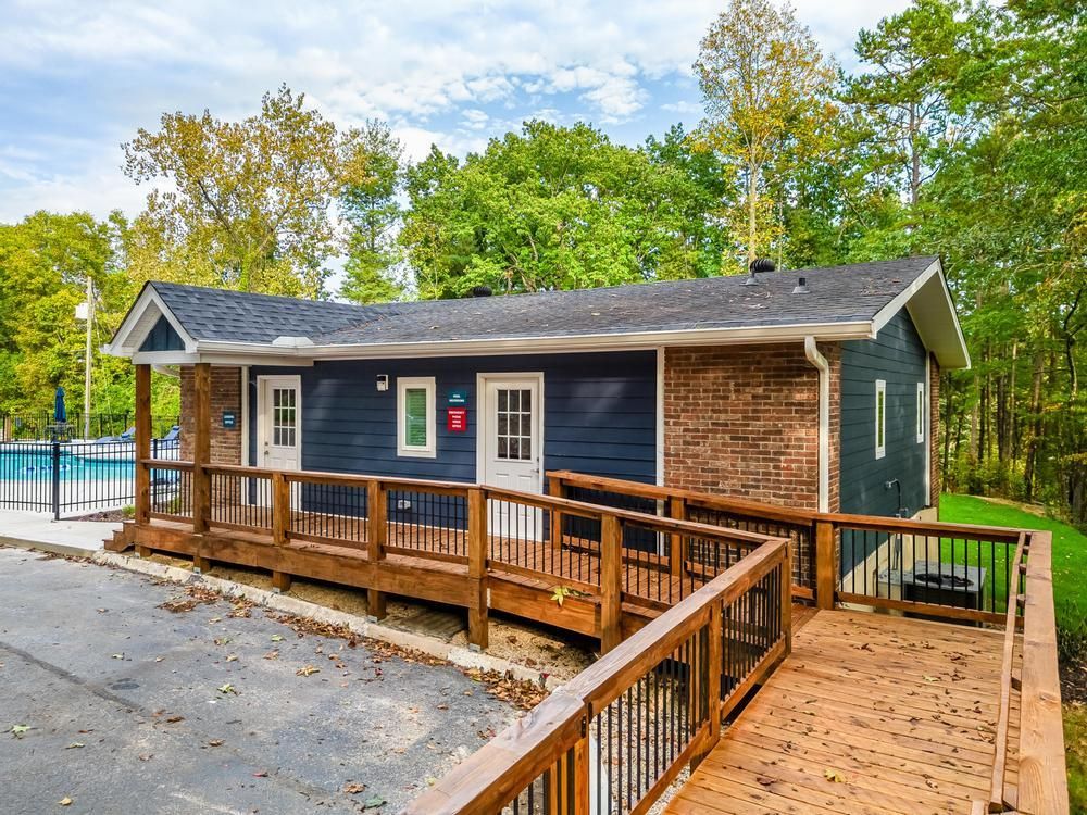 A small house with a wooden deck and a ramp leading to it.