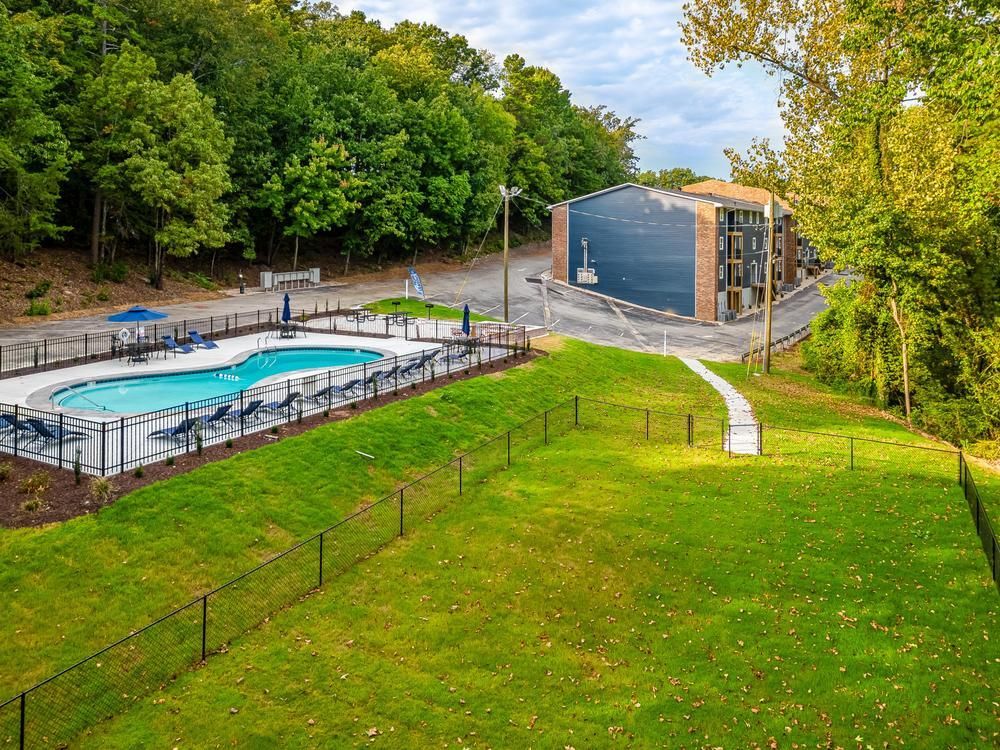 There is a large swimming pool in the middle of a lush green field.