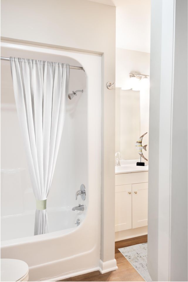 A bathroom with a bathtub, toilet, sink and mirror.