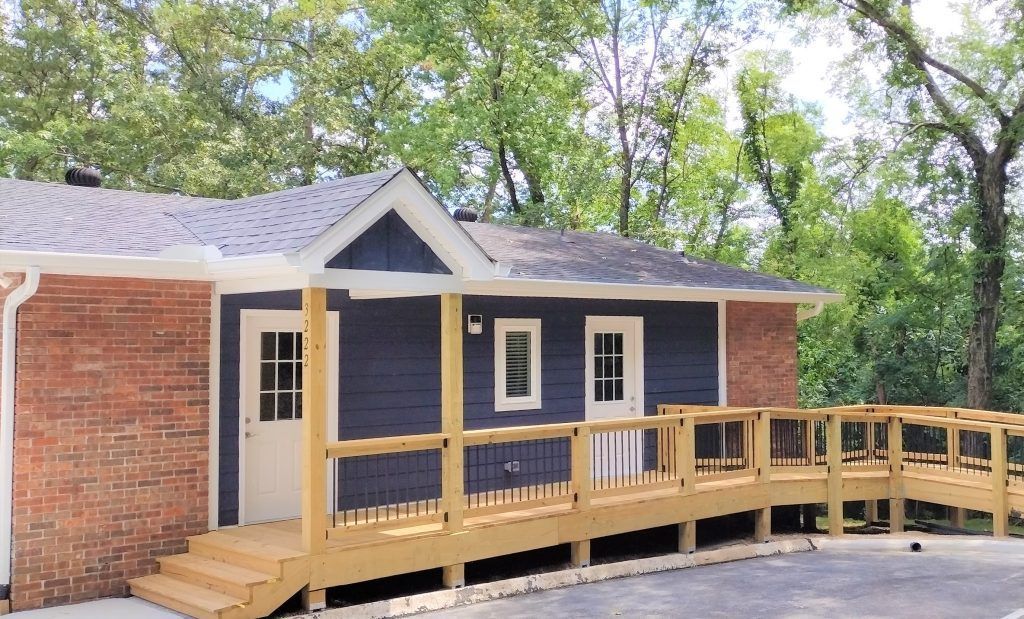 A small house with a wooden deck and stairs.