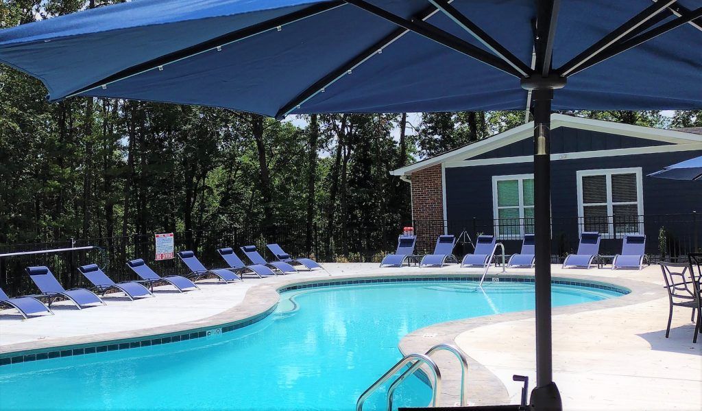 A large swimming pool with chairs and umbrellas around it.