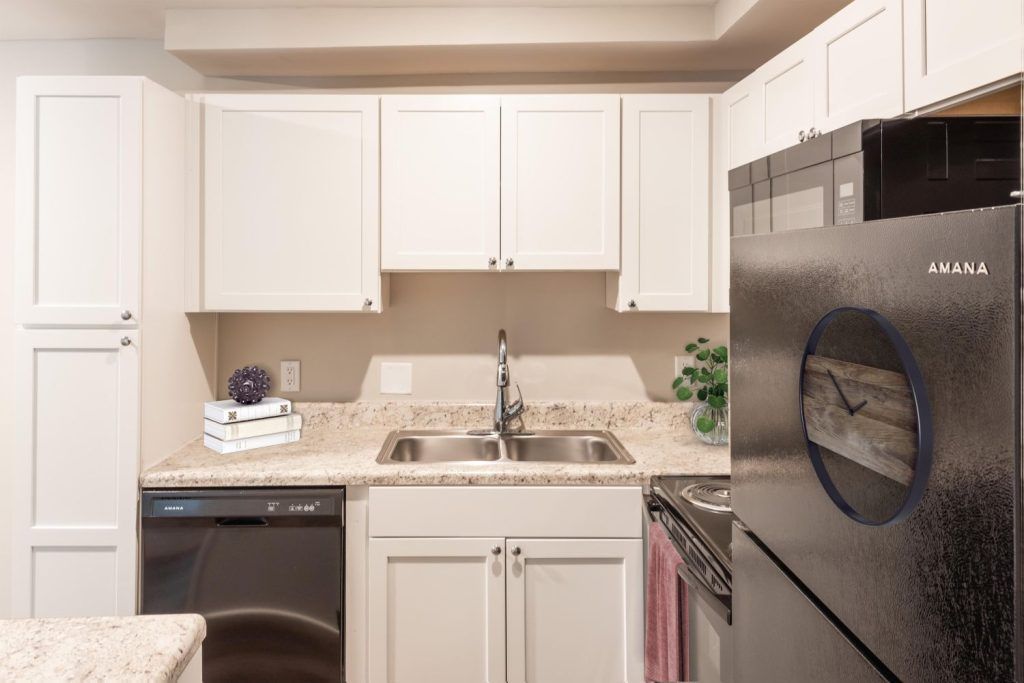 A kitchen with white cabinets, stainless steel appliances, a sink, and a microwave.