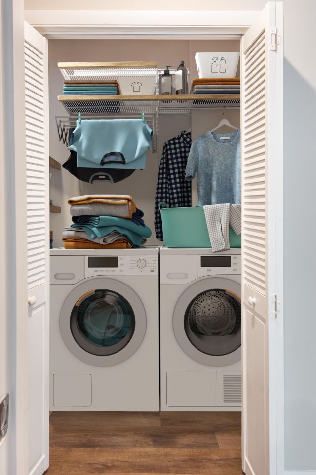 A laundry room with a washer and dryer and clothes hanging on the wall.