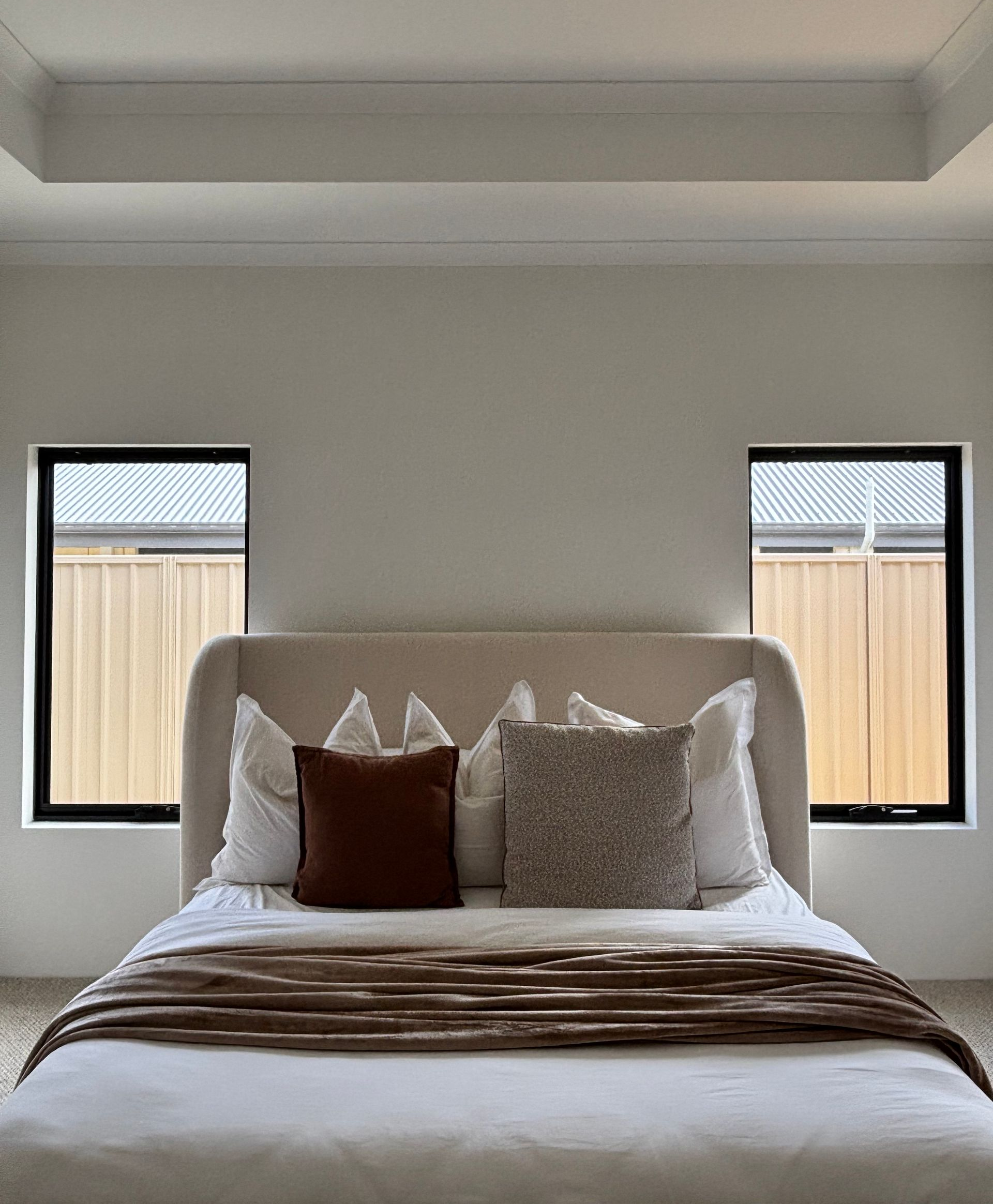 Plantation shutters installed in a glass enclosure with gold frame in a bright indoor room near a window in Joondalup, WA.