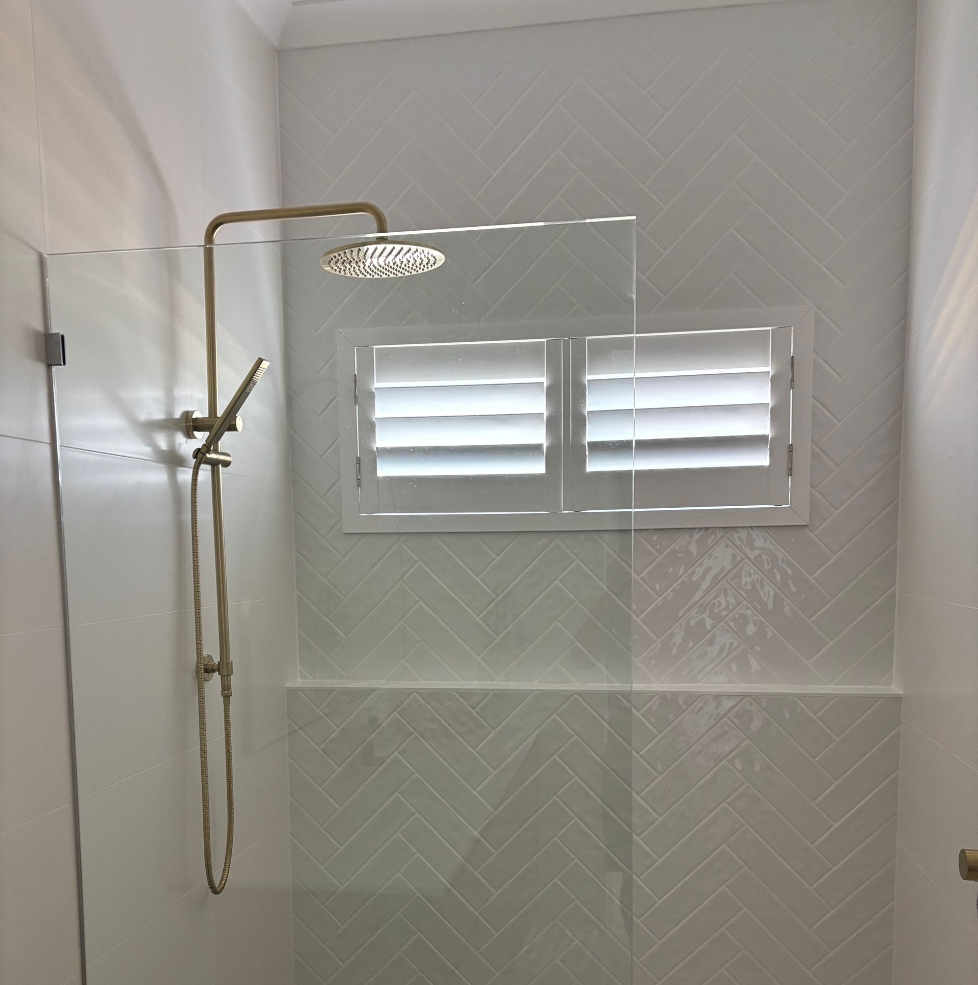 Plantation shutters installed in a living room wall with two windows and a centered yellow-and-black poster above beige carpet in Perth, WA.