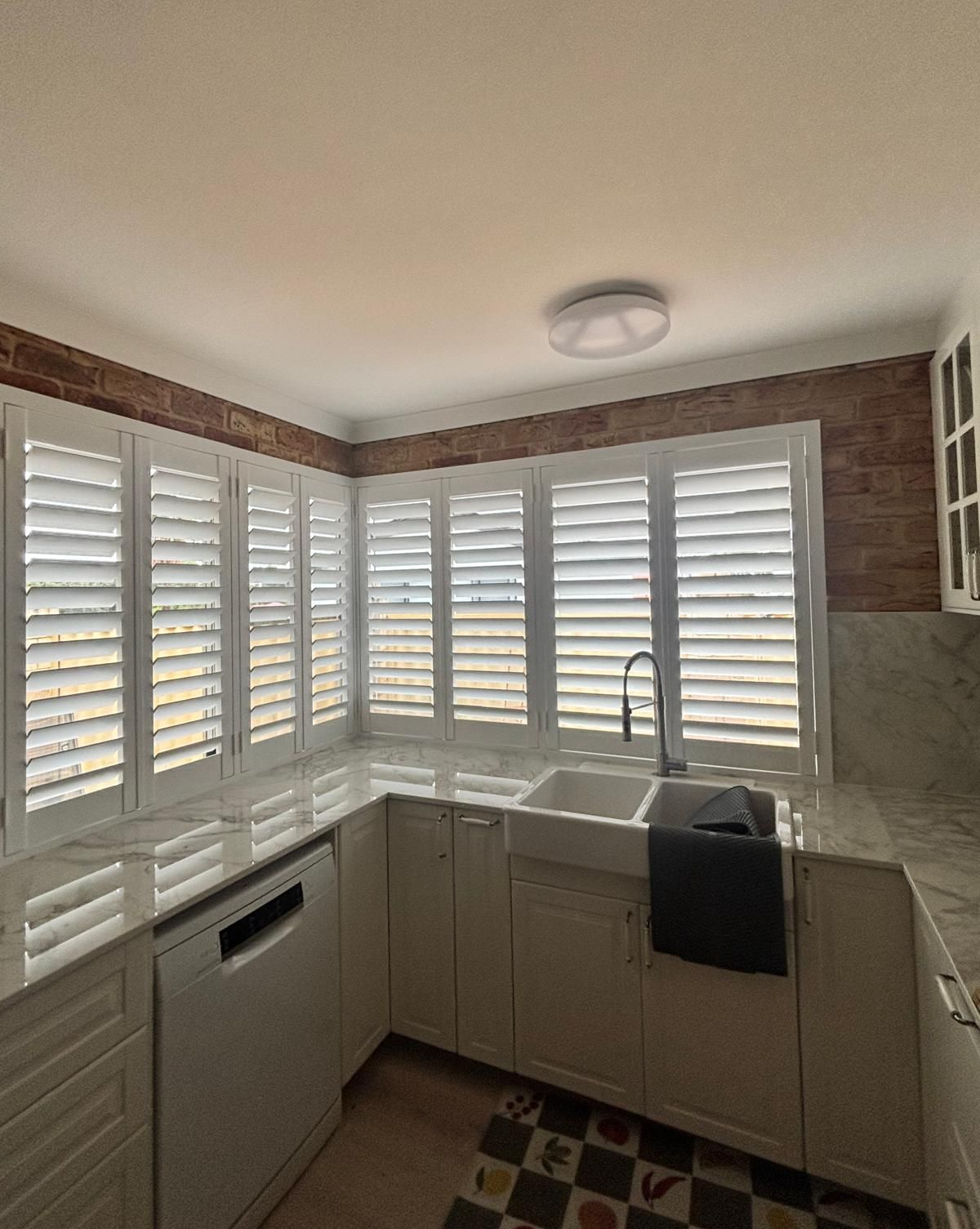 Plantation shutters installed in a bathroom with white plantation shutters above a corner soaking tub in Joondalup, WA.