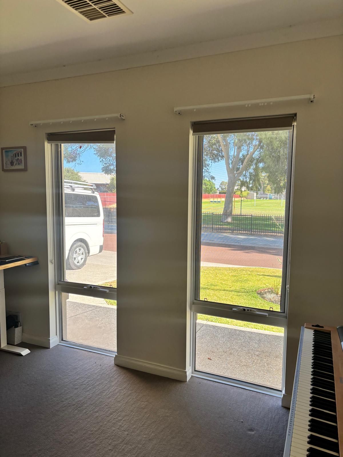 Plantation shutters installed in a large window with vertical blinds partially open, showing a white van and bright street outside in Joondalup, WA.