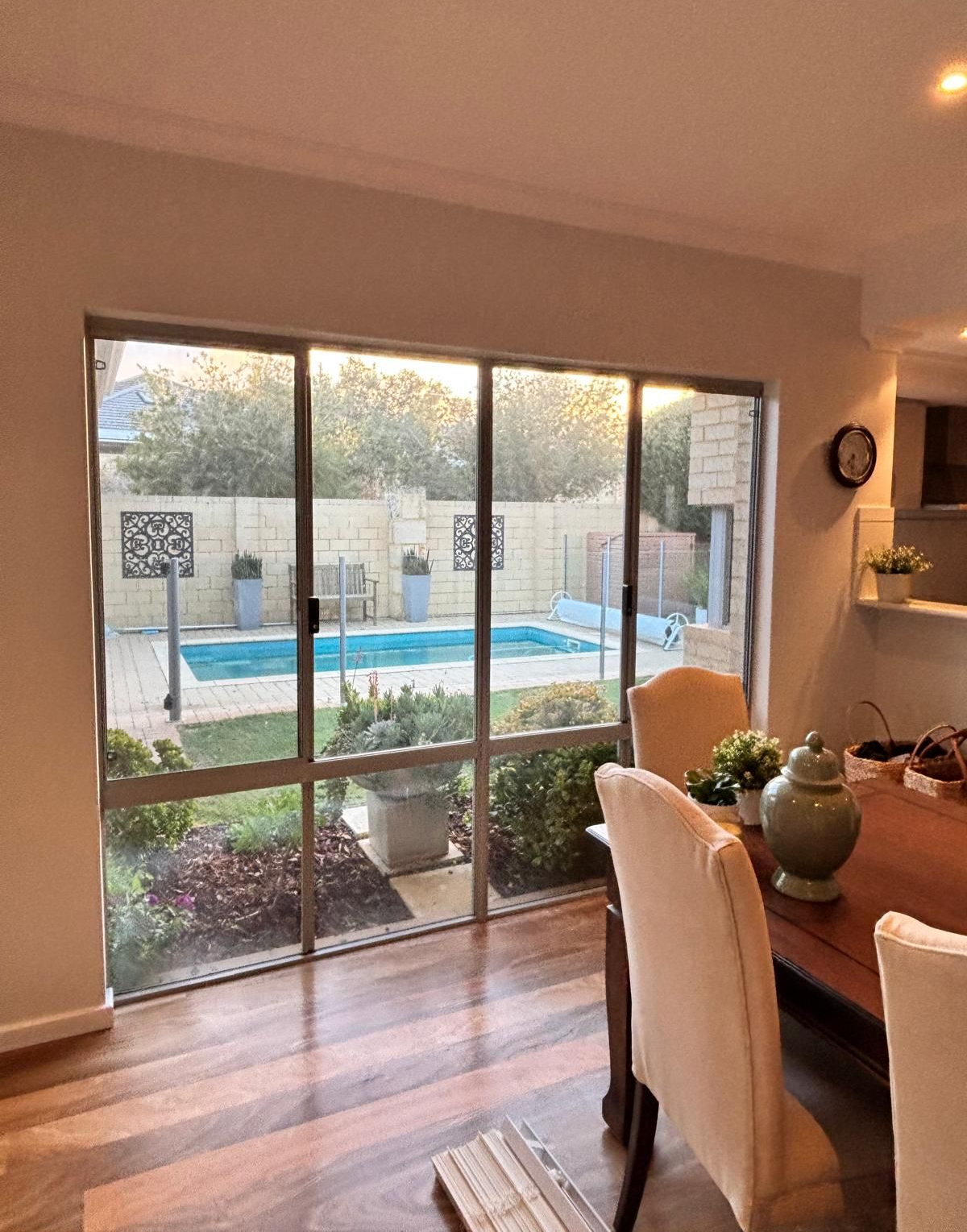 Plantation shutters installed in a sunlit bathroom with a corner tub and large windows overlooking trees and distant city buildings in Perth, WA.