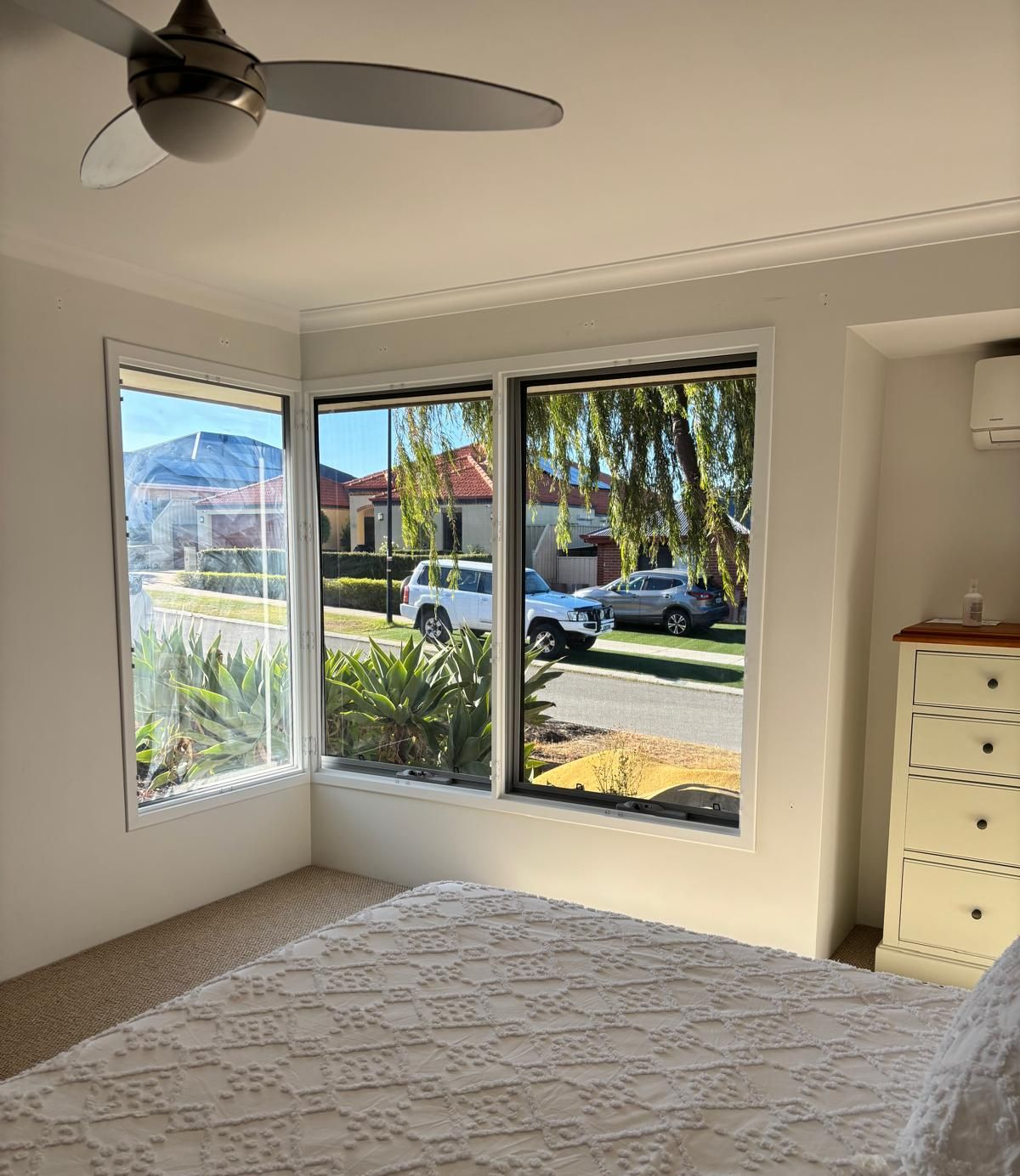 Plantation shutters installed in an unfurnished room with arched windows and open doors overlooking a rainy garden in Joondalup, WA.