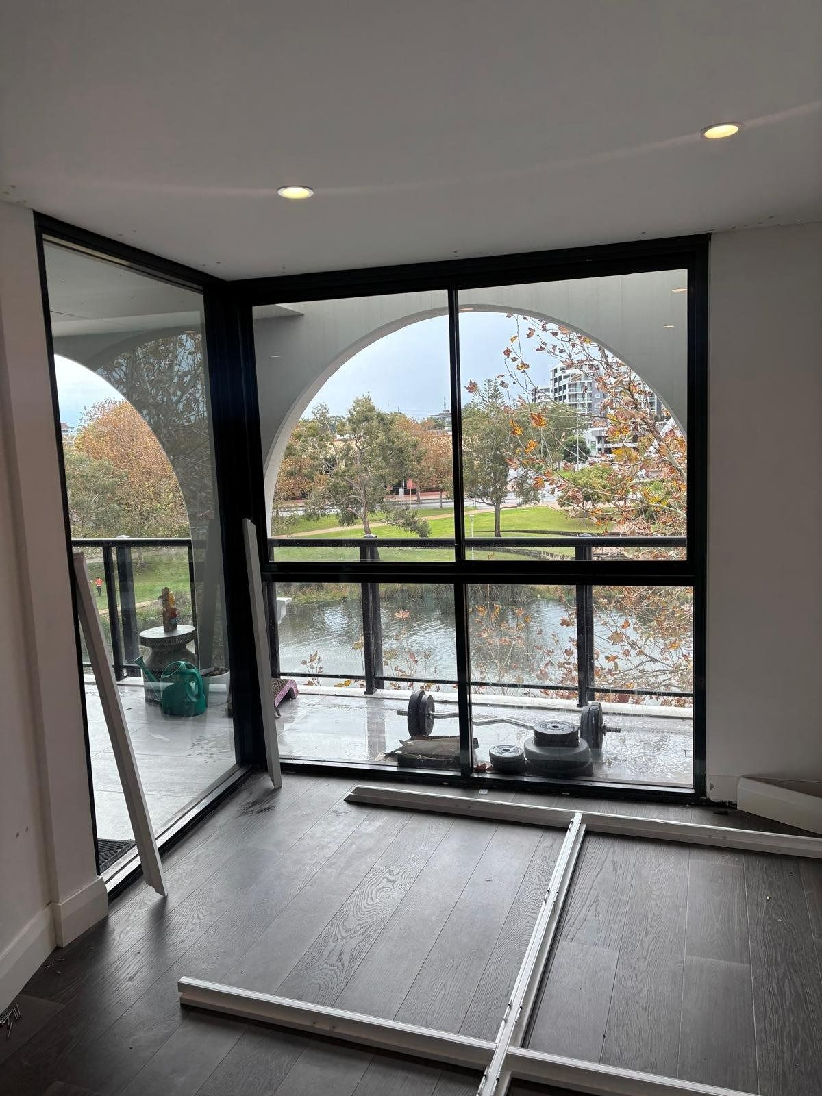 Plantation shutters installed in an unfurnished room with arched windows and open doors overlooking a rainy garden in Perth, WA.