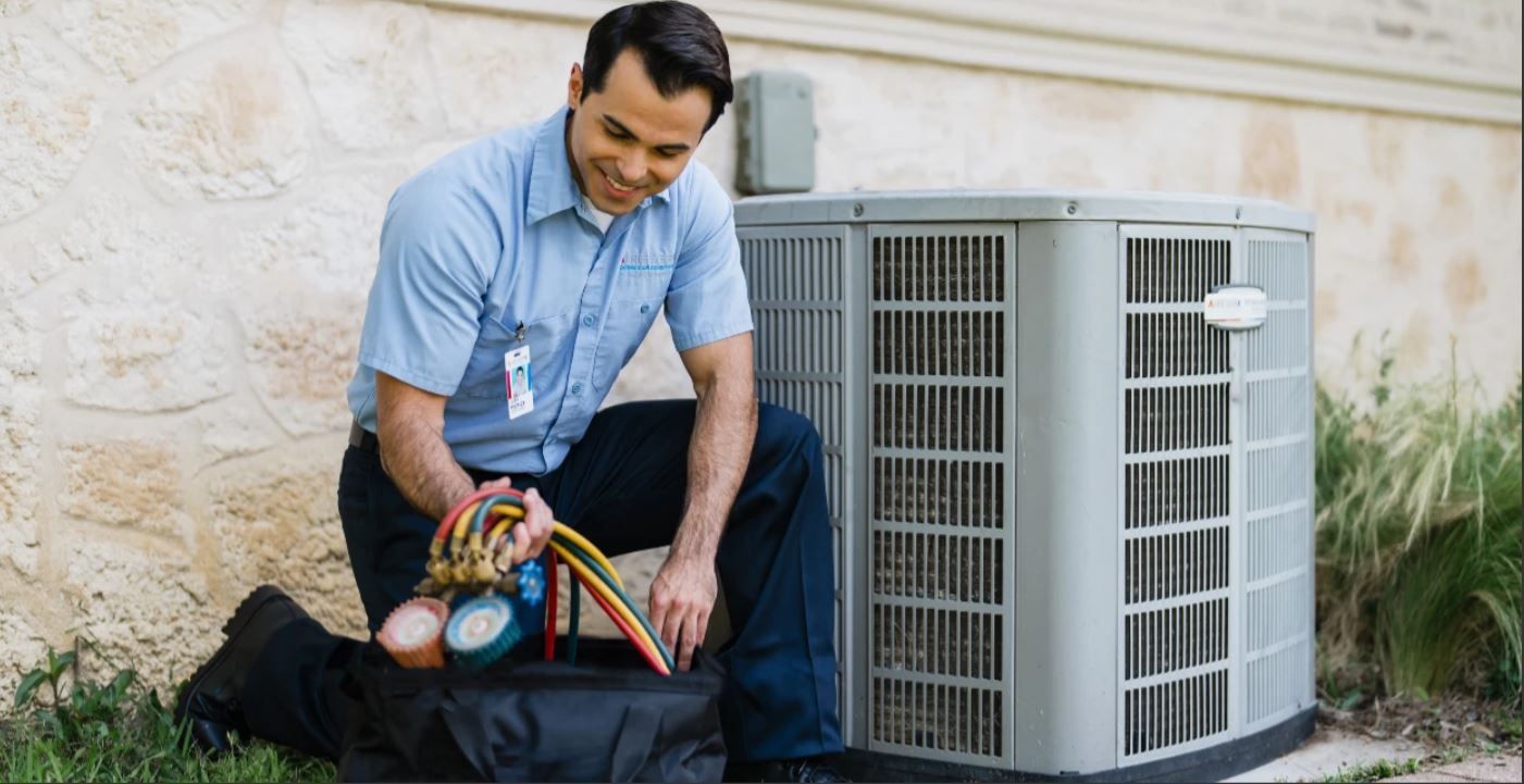 HVAC technician inspecting an outdoor air conditioning unit with pressure gauges