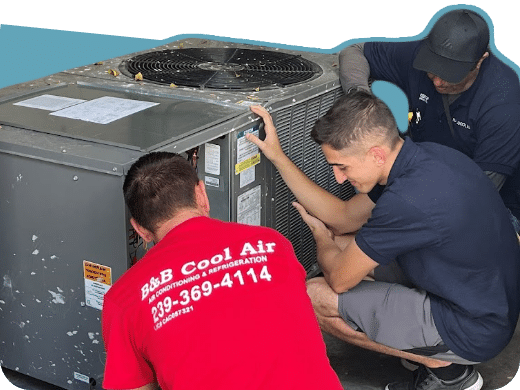 Three technicians working on an AC unit. One in red shirt, two in blue.