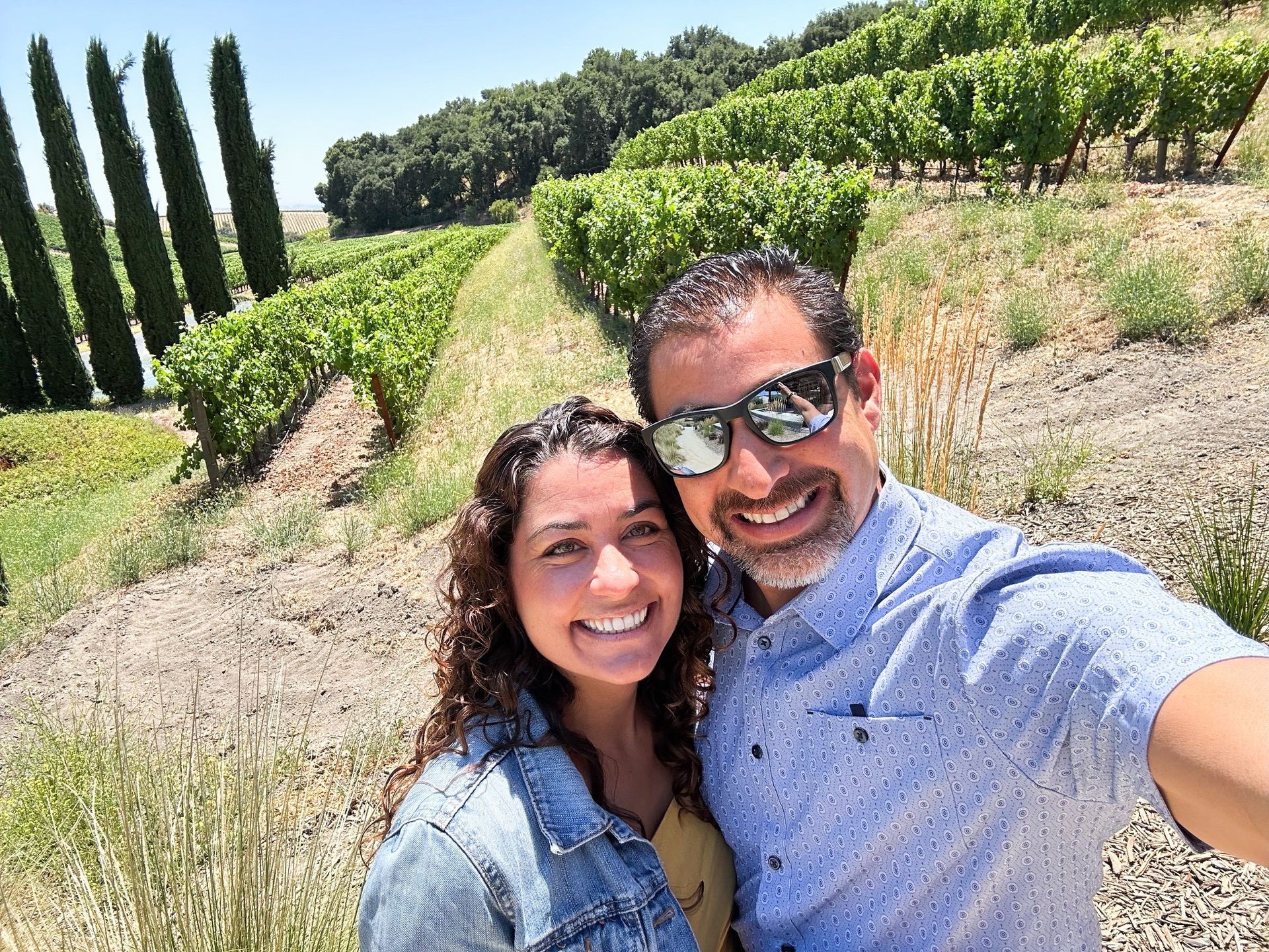 A man and a woman are taking a selfie in a vineyard.