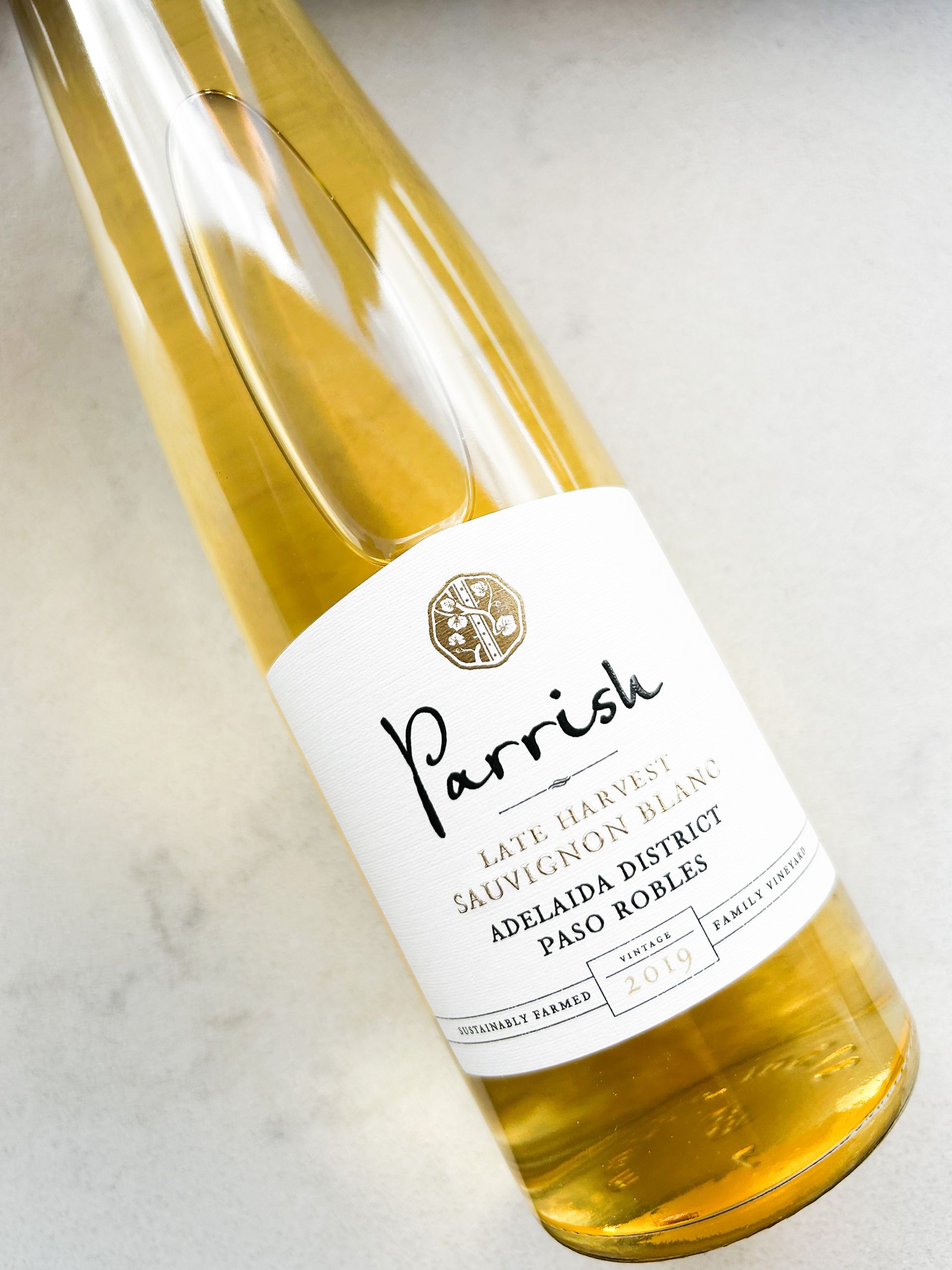 A bottle of 2019 Parrish Late Harvest Sauvignon Blanc dessert wine lying on a  white marble countertop.