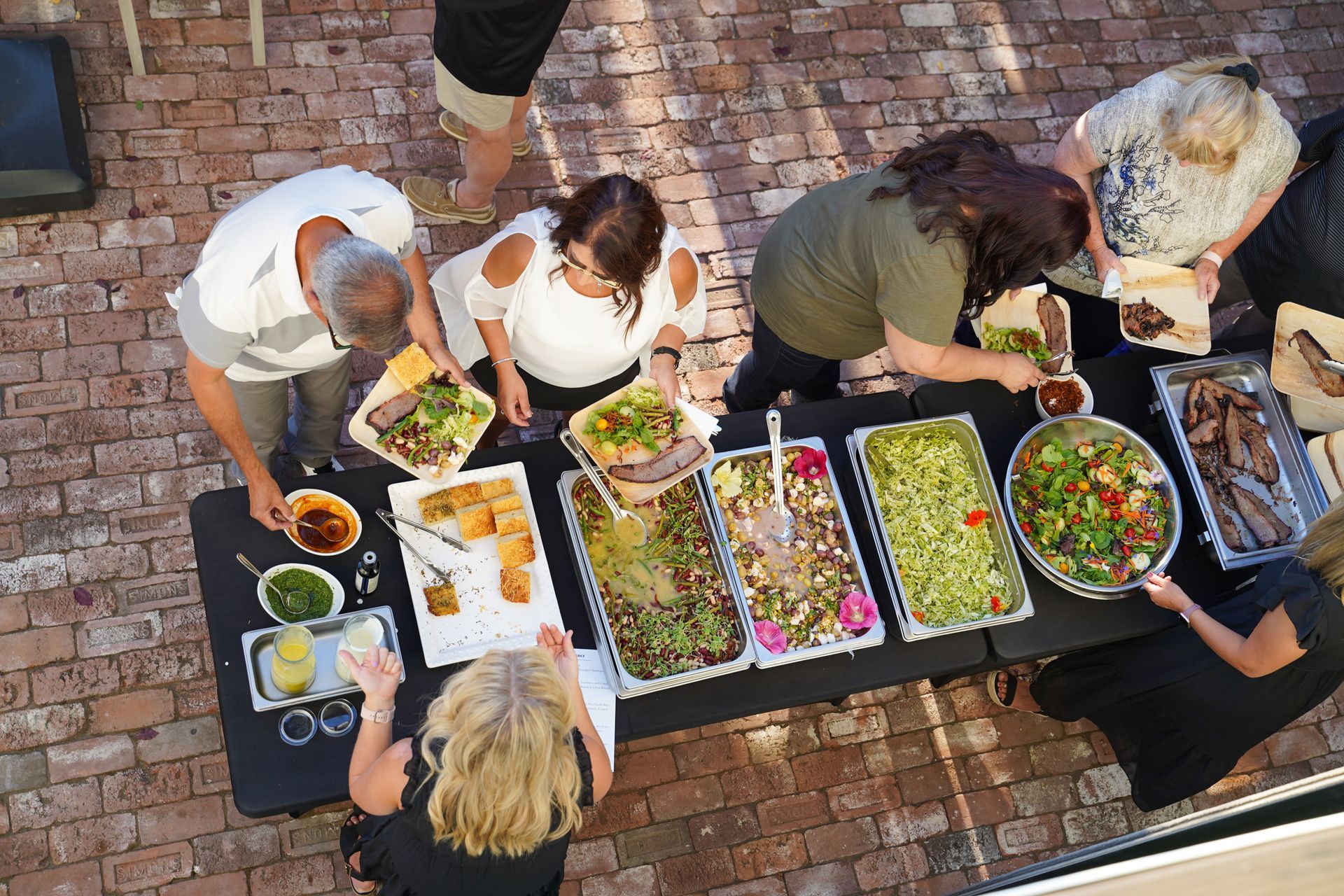Guests of the Parrish Family Vineyard anniversary party gather around a buffet table, serving themselves dinner prepared by our estate chef.