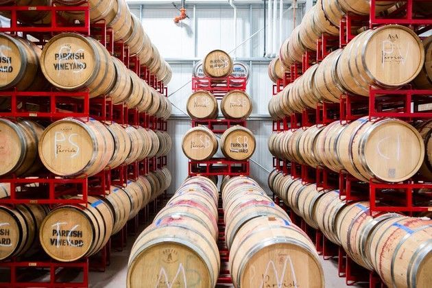 A warehouse filled with lots of wooden wine barrels stacked on top of each other.