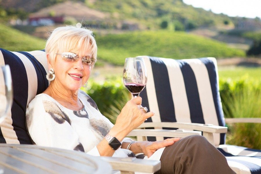 A lady on an armchair with a glass of wine in hand.