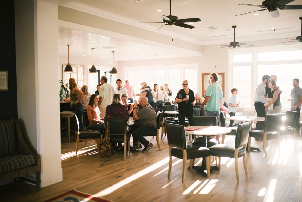 A group of people are sitting at tables inside the tasting room.