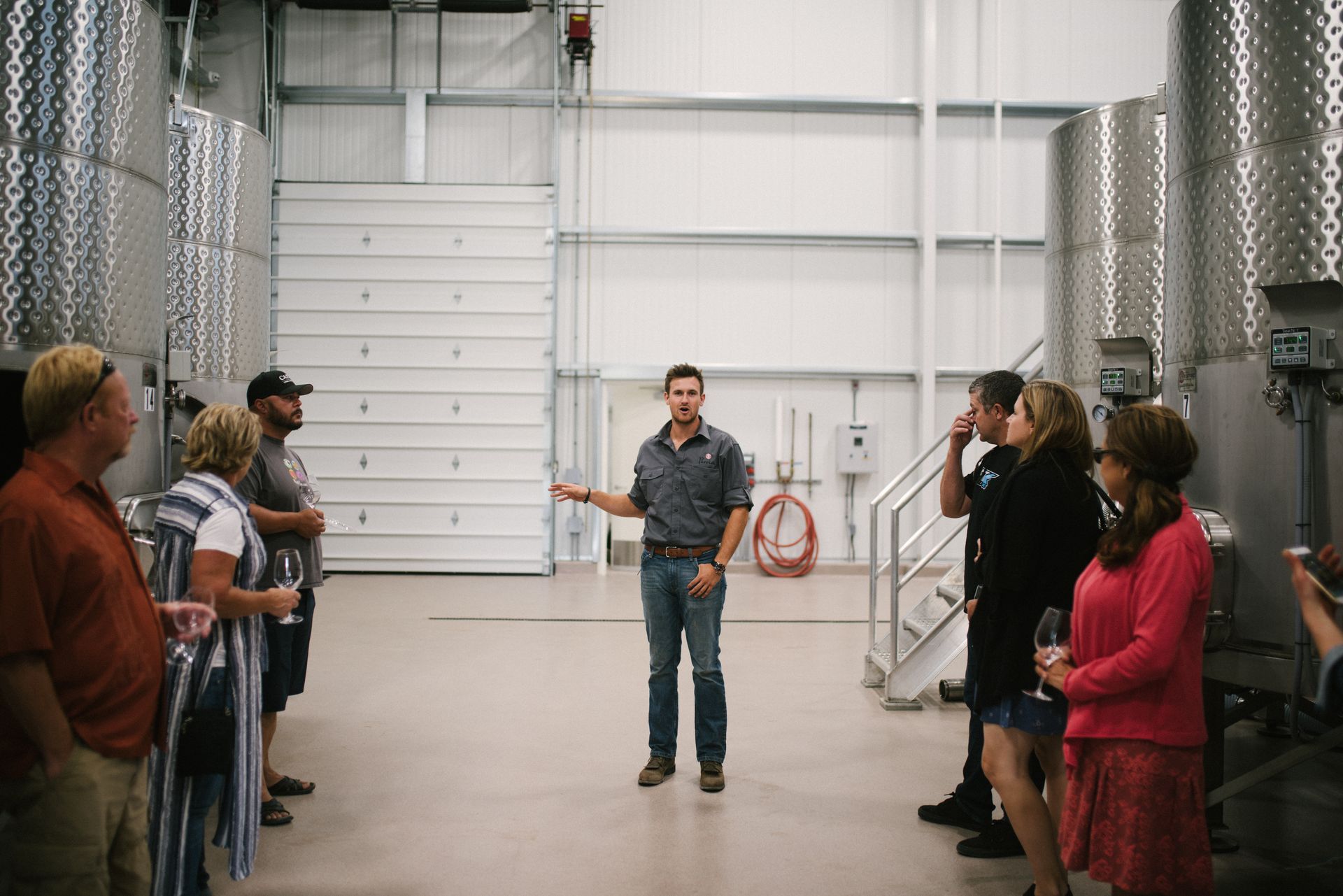 Winemaker Cody Alt leading guests on a tour through the production winery, pointing to the stainless steel tanks where the Parrish team ferments wines before aging and bottling.