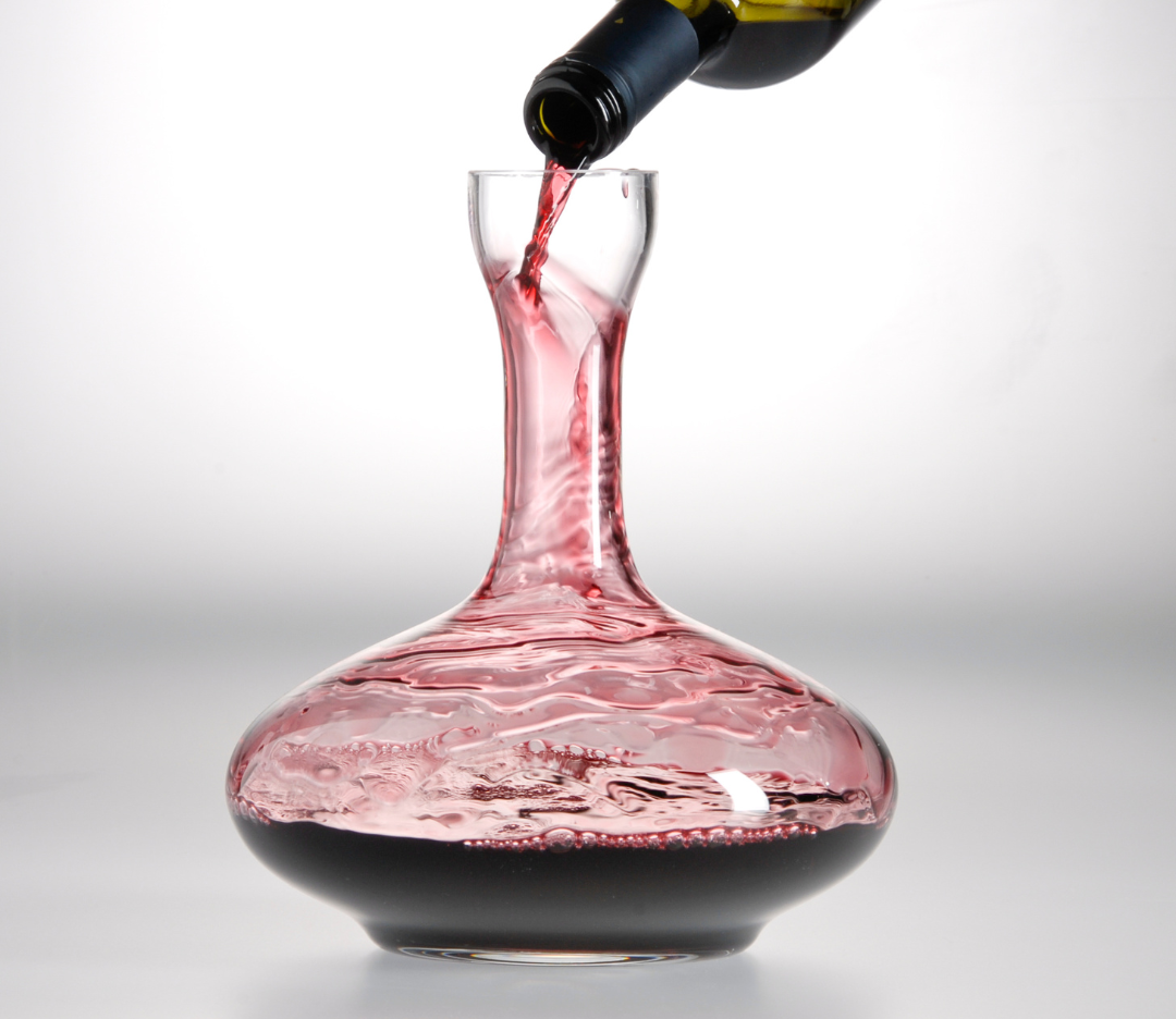 Red wine being poured into a decanter.